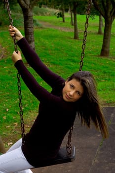 A pretty woman on a swing in a play park