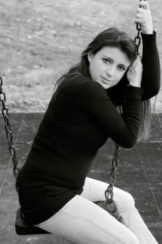 black and white image of pretty young female on a swing