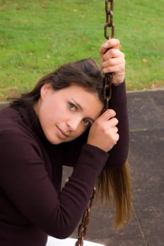 Pretty woman sitting on a swing. 