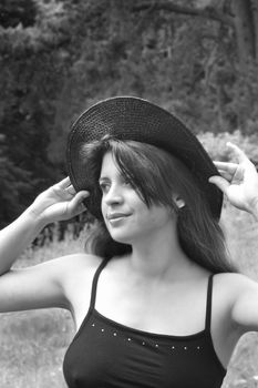 a black and white of a happy, attractive young lady wearing a hat in summer