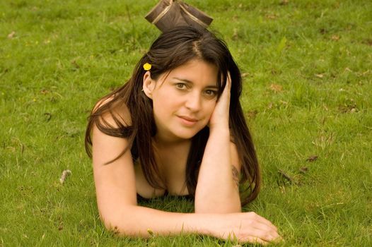 a pretty woman lying in a field with a flower in her hair