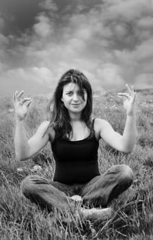 a black and white of a woman medetating in a field