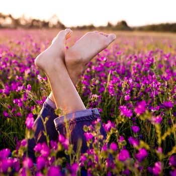 Female crossed legs on a beautiful flowery meadow