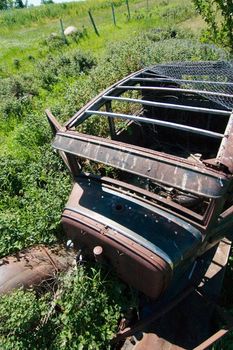 An old rusted out car on the prairie landscape