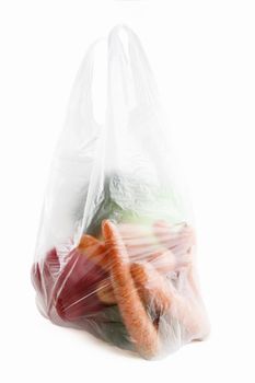 Healthy vegetables in a clear plastic grocery bag on a white background