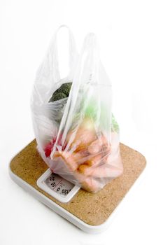 Healthy vegetables in a clear plastic grocery bag on a scale