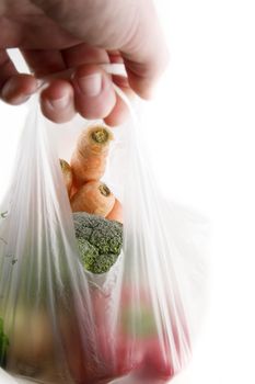 A clear plastic grocery bag filled with vegetables, a healthy choice