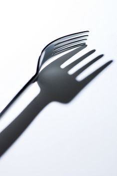 Fork and his expressive shadow on white background.