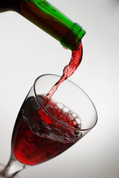 Pouring red wine from green bottle.