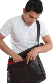 Male student placing a book into a brown leather satchel.  White background