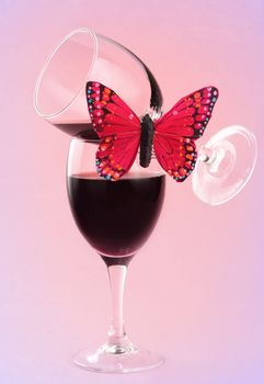 glass of red wine with fake butterflies