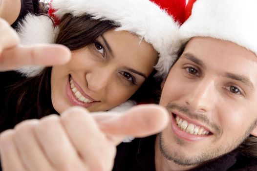 close up view of young couple wearing christmas hat and looking at camera against white background