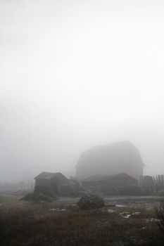 Abandoned farmyard engulfed in fog.