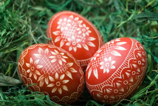 Three handmade easter eggs on the green hay. Selective focus, shallow depth of field.