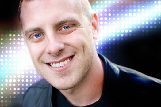 Closeup of the face of a happy young man with a big smile.  Abstract glowing halftone effects in the background.