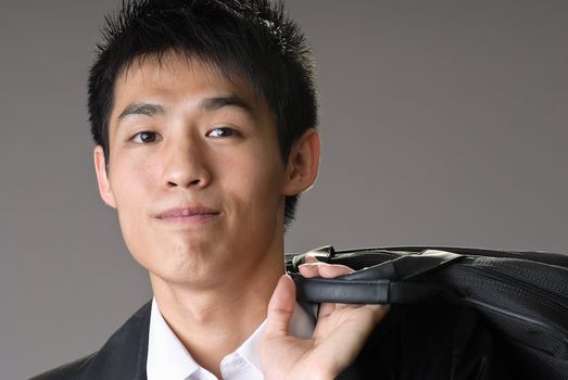 Portrait of young handsome business man of Asian with briefcase over shoulder.