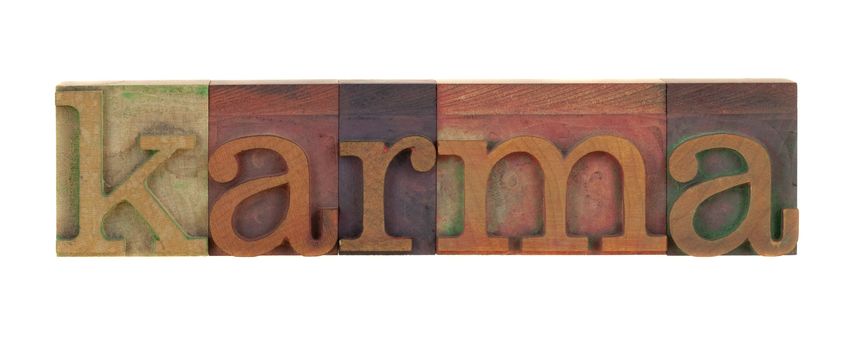 the word karma in vintage wood letterpress type blocks, stained by color ink, isoalted on white