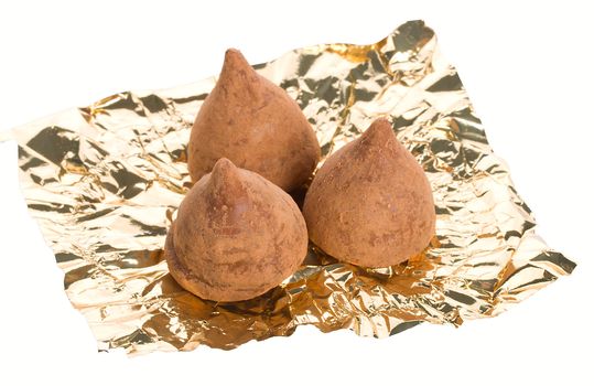 close-up three truffles on foil, isolated over white background