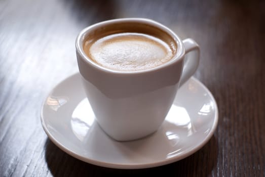 Cup of coffee on the cafe table. Shallow depth of field (focus on the froth surface).