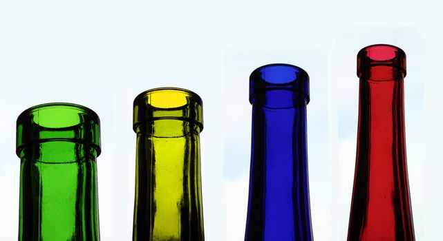 four glass bottles in different colours, red, yellow, blue, green