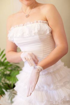 beautiful bride puts on a white glove
