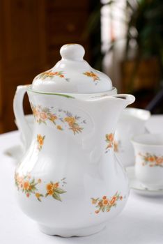 Coffee or tea set on the table - teapot on the front (focus on it) cups and milk jug behind. Shallow DOF.