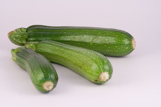 Freshly picked courgettes on white.