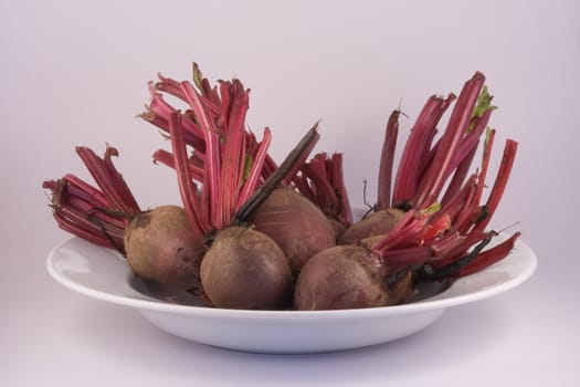 Freshly harvested beetroot on a plate on white.
