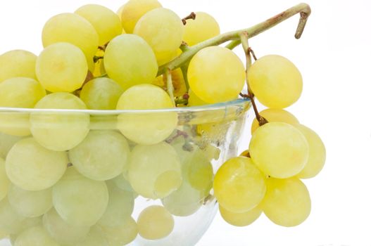 Close and low level angle capturing a glass bowl of grapes arranged over white.