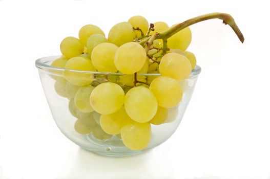 Close and low level capturing a glass bowl containing a bunch of fresh green grapes isolated over white.