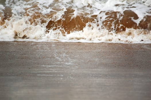 A Wave splash on sand, focus on sand