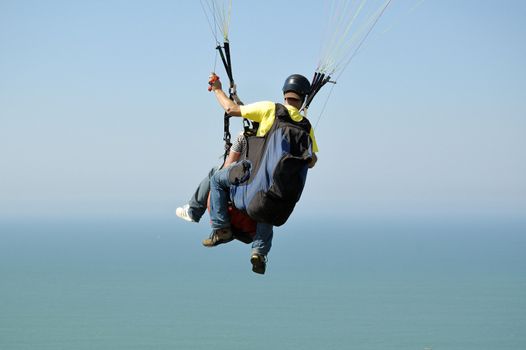 Double Paragliding flying throught the sky above the ocean