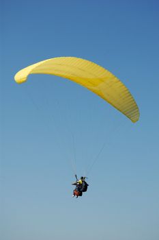 Double Paragliding flying through the sky above the ocean