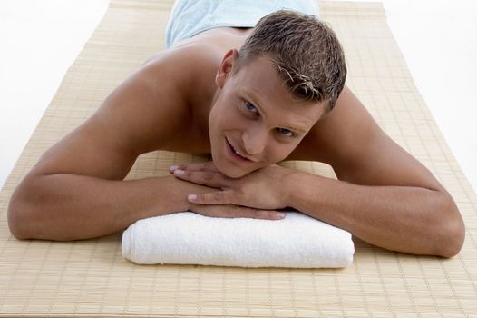 young male lying on mat ready to take spa treatment on an isolated white background