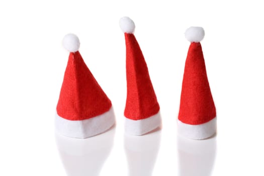 Three cute red small santa hats on white background