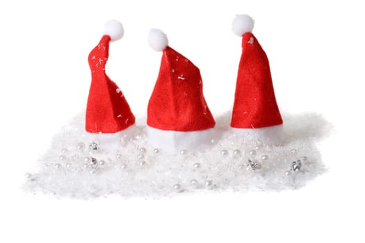 Three little christmas hats in the snow on white background