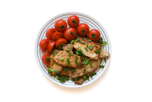 Fried meat with tomatoes on a plate.