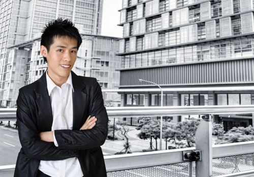 Young businessman standing outside of office buildings.