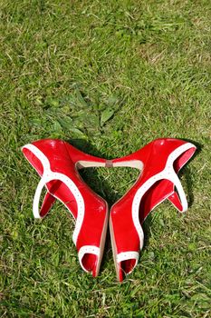 a pair of red high heels on a grass lawn in a heart shape depicting womans love of shoes