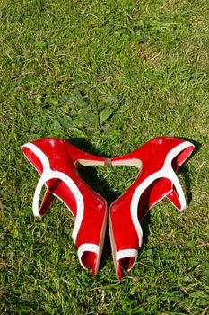 a pair of red high heels on a grass lawn in a heart shape depicting womans love of shoes