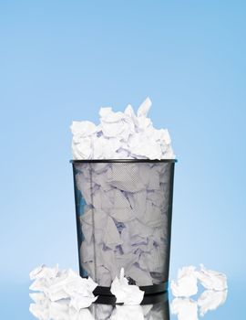 Filled wastebasket on blue background