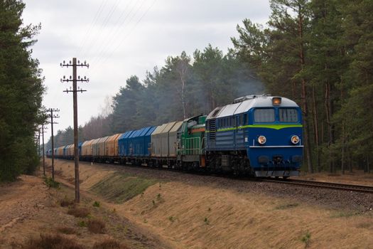 Freight train hauled by two diesel locomotives passing the forest
