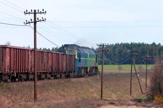 Freight train hauled by two diesel locomotives passing the forest
