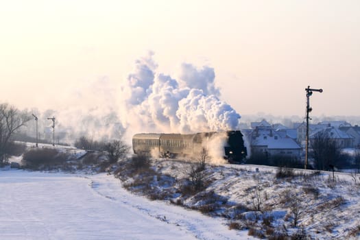 Vintage steam train passing through snowy countryside
