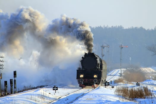 Vintage steam train passing through snowy countryside