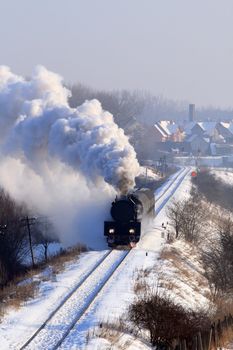 Vintage steam train passing through snowy countryside