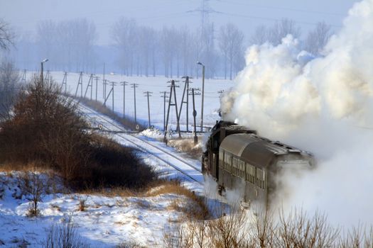 Vintage steam train passing through snowy countryside