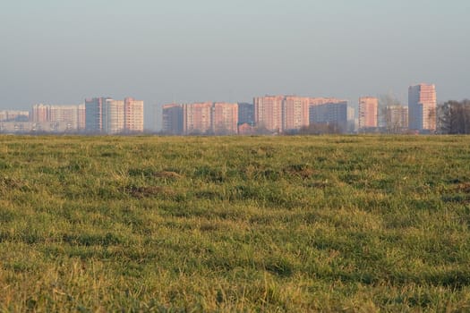 View of Shcherbinka town from a misted grassy autumn field