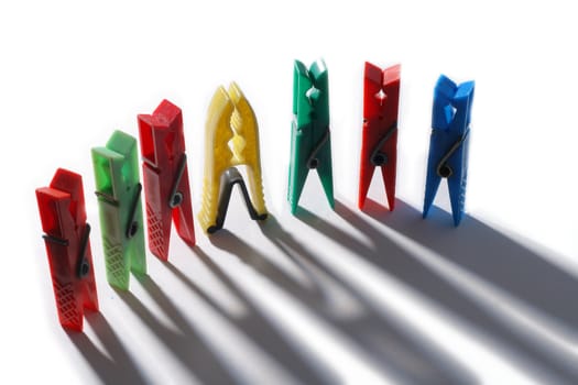 Colorful clothes pegs in a row with shadows
