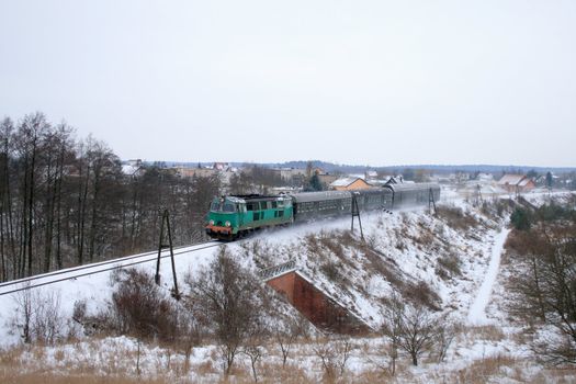 Rural winter landscape with train hauled by the diesel locomotive